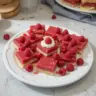 Plate of homemade lemon raspberry bars with a zesty citrus and berry topping