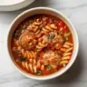 Delicious bowl of homemade meatball soup with fresh vegetables and herbs