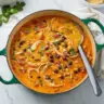 Bowl of savory Chicken Enchilada Soup topped with cheese and cilantro