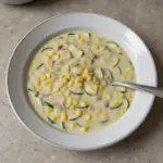 Bowl of summer corn zucchini chowder garnished with herbs