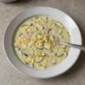 Bowl of summer corn zucchini chowder garnished with herbs
