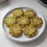 Plate of crispy zucchini corn fritters garnished with herbs