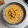 Bowl of cheesy beef and potato soup topped with melted cheese and herbs.