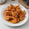 Plate of hot honey fried shrimp garnished with herbs