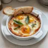 Italian baked eggs served in a skillet with fresh herbs and vegetables