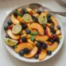Peach fruit salad with honey lime dressing in a bowl