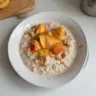 Bowl of delicious peach overnight oats topped with fresh peach slices