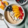 Peaches and Cream Smoothie Bowl topped with fresh fruit and granola