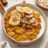 Bowl of quick pumpkin oatmeal topped with nuts and spices
