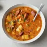 Bowl of Spanish potato soup with chorizo garnished with herbs