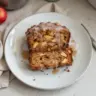A slice of spiced apple fritter bread topped with glaze and apples