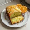 Delicious zucchini orange cake topped with orange zest and served on a plate.