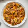 Grilled Jalapeño Peach Chicken garnished with fresh herbs on a plate.